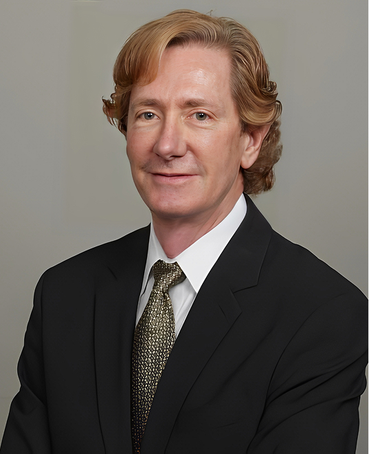 Portrait of Mack Stewart, MD, in a dark suit and tie