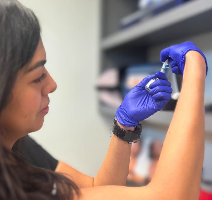 A Pure Radiance staff member in blue gloves drawing up an injectable from a vial