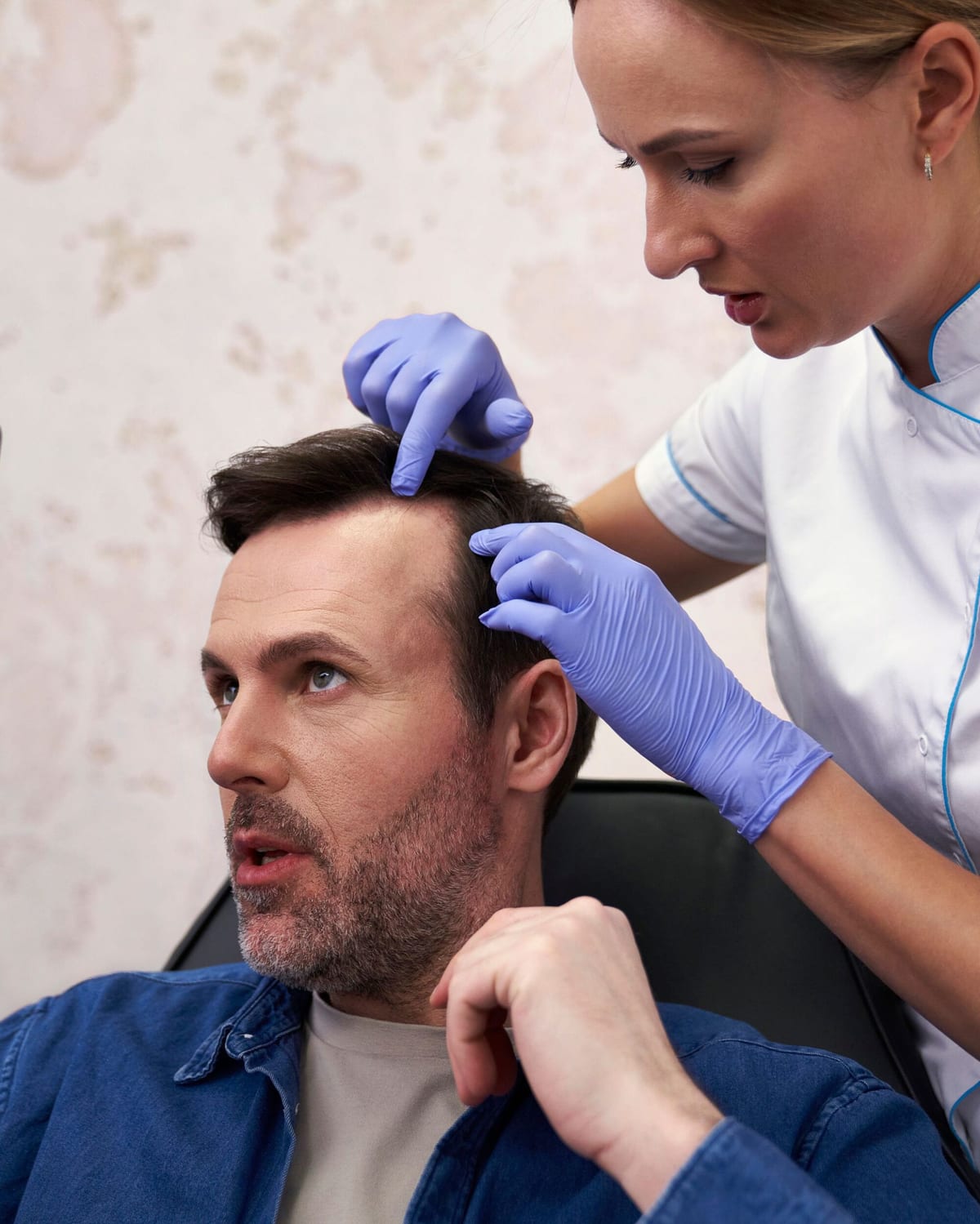 A clinician in gloves examining a model's scalp
