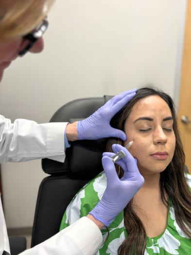 A provider in gloves injecting filler beside a woman's eye