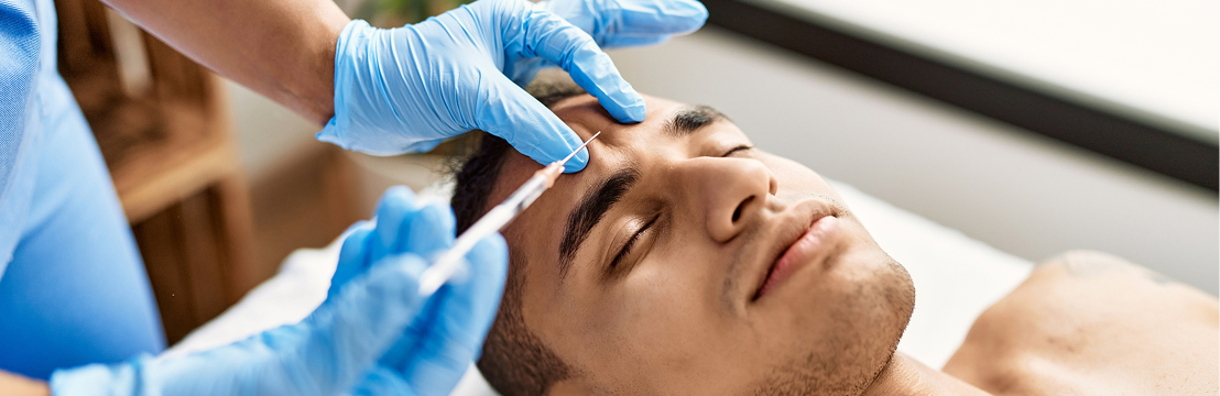 A model receiving a forehead injection from a provider in blue gloves