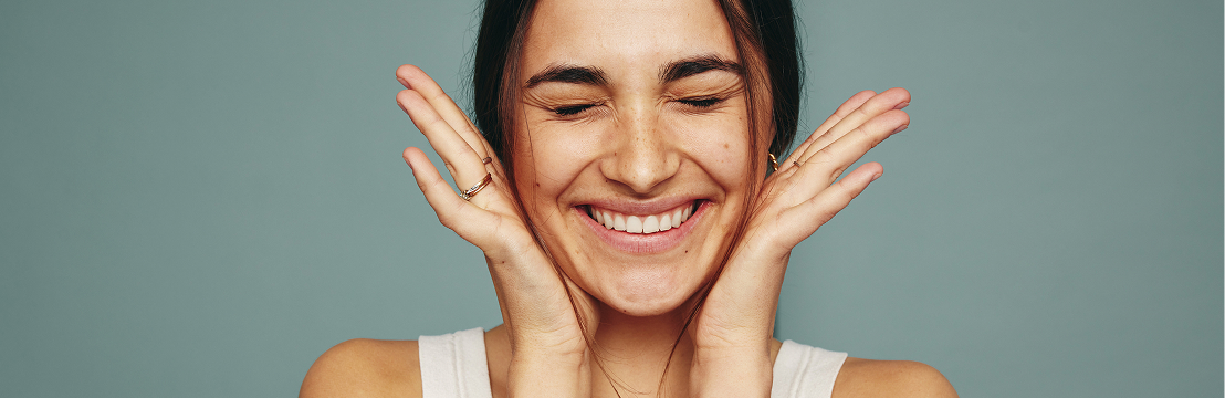 A smiling model with her hands framing her face