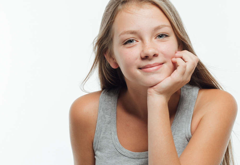 Teen girl with clear skin resting her chin on her hand, representing early acne care and teen skincare guidance. Teen girl with clear skin resting her chin on her hand, representing early acne care and teen skincare guidance.